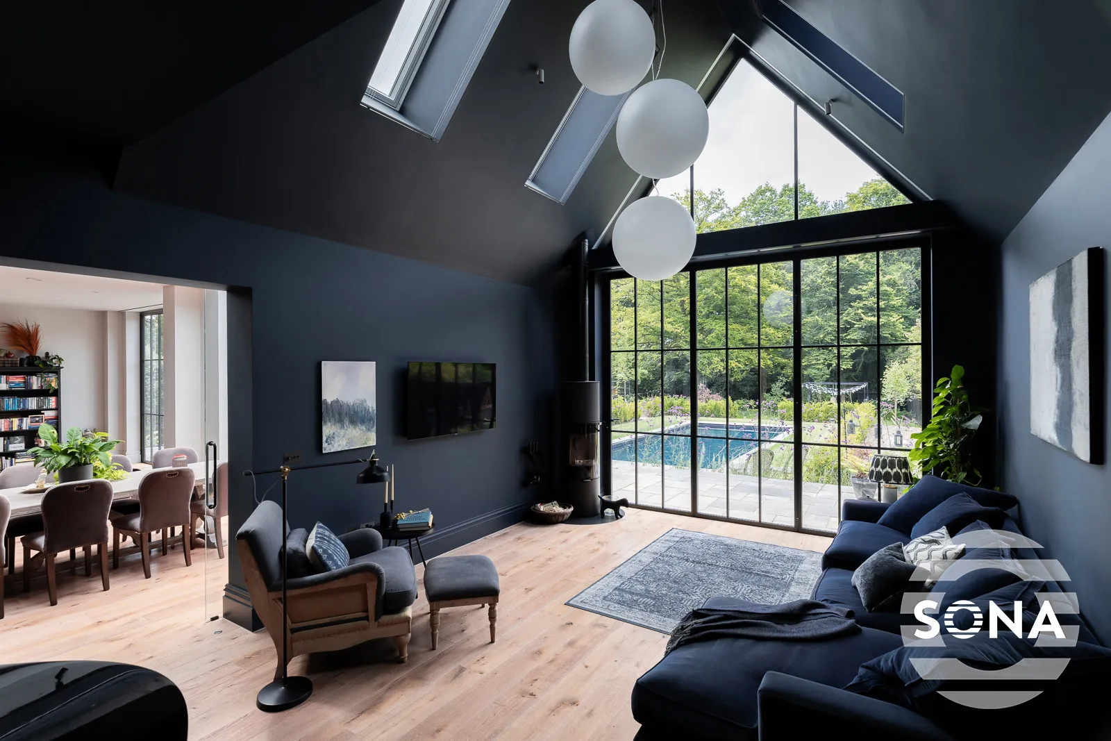 A gable end window covered by electric gable blinds in a light spacious room looking on to an outdoor swimming pool
